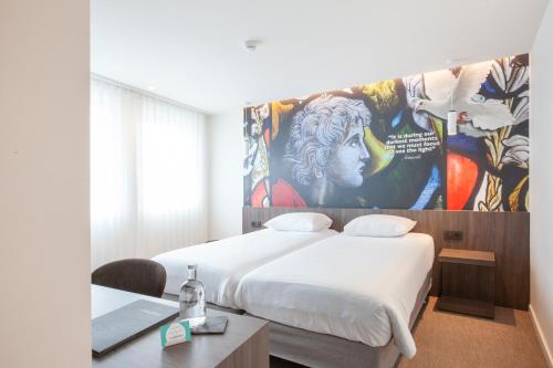 a room with a bed and a desk and a painting at Hotel The Shepherd in Leuven