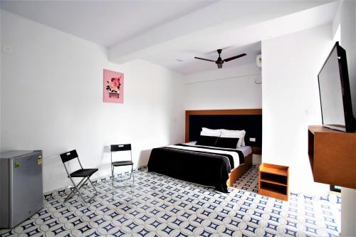 a bedroom with a bed and two chairs and a tv at TM Calangute House Stay at Goa in Calangute