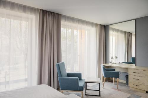 1 dormitorio con 1 cama, escritorio y sillas en Magnus Resort, en Szczyrk