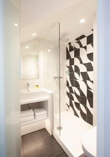 a bathroom with a glass shower and a sink at Hotel The Shepherd in Leuven