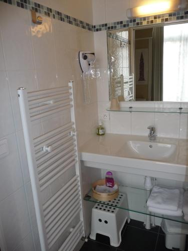 une salle de bain blanche avec un lavabo et un miroir dans l'établissement Au Troubadour, à Hellemmes-Lille