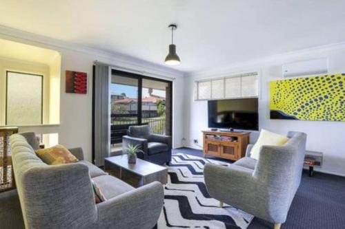 a living room with a couch and chairs and a television at Bright Private Room in Pleasant Ashmore in Gold Coast