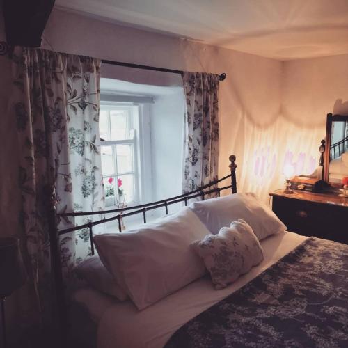 a bedroom with a bed with pillows and a window at Cissy's Cottage - traditional thatched cottage, on the Causeway Coast in Aghanloo