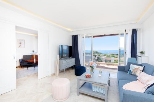 un salon avec un canapé bleu et une télévision dans l'établissement Suite Riviera - Sea View - Clim - 50M Plage - Residence de standing - Spacieux 180 M2 - Parking, à Cannes
