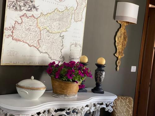 a table with flowers and a lamp and a map at Vicosuite Neathon in Noto