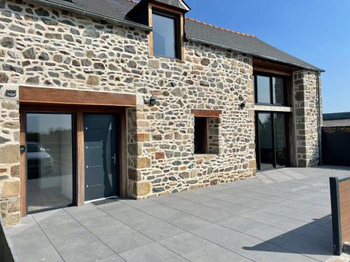 Cette maison en pierre dispose de portes vitrées et d'une terrasse. dans l'établissement Magnifique corps de ferme rénové avec Jacuzzi, à Hillion