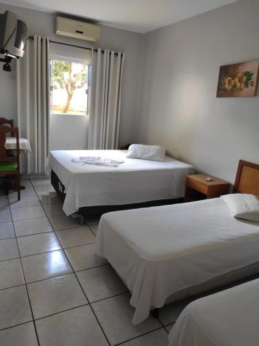 MineirosPlaza Hotel的酒店客房设有两张床和窗户。