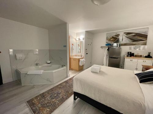 1 dormitorio con 1 cama y bañera en una habitación en Private Room On Waterfront Property With Hot Tub Firepit - Sea Esta en Ucluelet