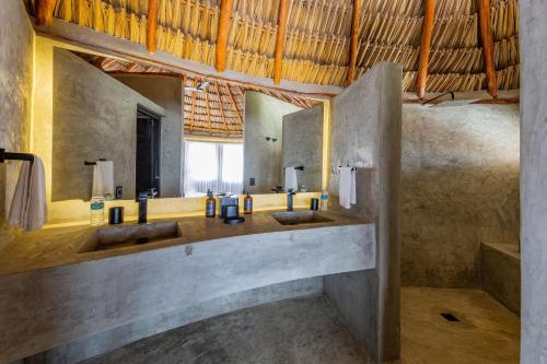 a bathroom with two sinks and a large mirror at Maya Tulum By G Hotels in Tulum