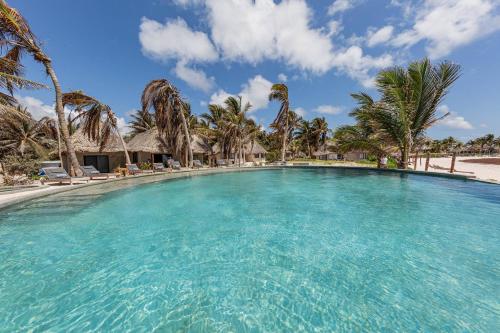 a large swimming pool with palm trees on a beach at Maya Tulum By G Hotels in Tulum