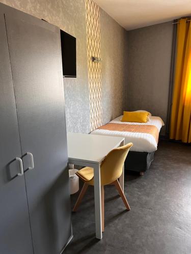 a small room with a bed and a table and a desk at Hotel Alpes Cevennes in Guilherand