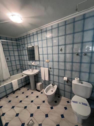 W wyłożonej niebieskimi kafelkami łazience znajduje się toaleta i umywalka. w obiekcie Hotel Serantes w mieście O Grove