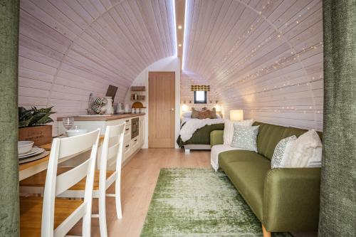 a living room with a green couch and a bed at Tan Y Bryn Glamping in Conwy