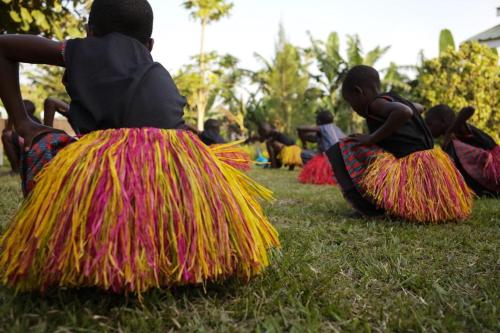 a group of children sitting on the grass at Mwamba Kelele Lodge in Fort Portal