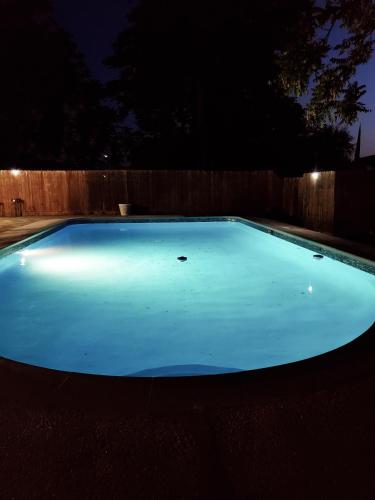a large blue swimming pool in a backyard at night at Garden Clara in Yuba City