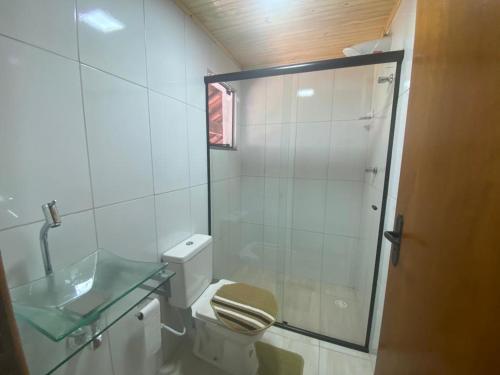 um banheiro com vaso sanitário e box de vidro em Recanto dos Fernandes em Monte Verde