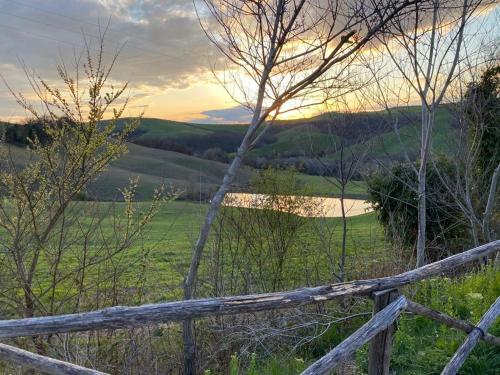 a wooden fence in a field with a sunset in the background at La casina di Helen in Montalcino