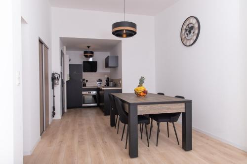 une cuisine et une salle à manger avec une table et des chaises noires dans l'établissement Appartement 70m2 hyper centre avec baignoire balnéo, à La Flèche