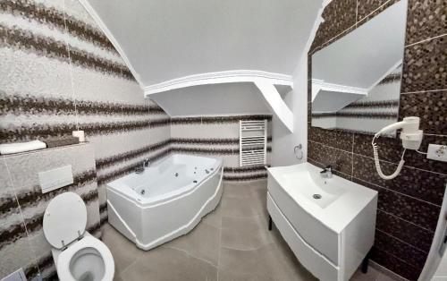 a bathroom with a white toilet and a sink at Vila Bun in Baile Felix