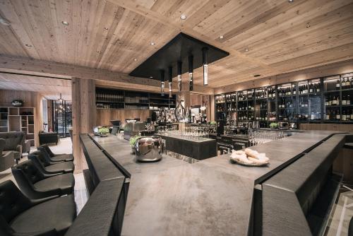 a bar with black chairs and a counter with wine bottles at Tenne Lodges in Racines