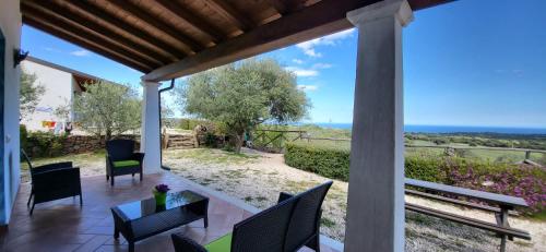 a patio with a table and chairs and a view of the ocean at Agriturismo Su Barcu in Cala Gonone