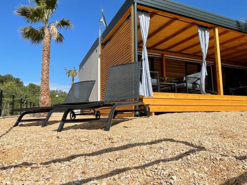 two chairs and a bench in front of a house at Mobile Home BARTOL de LUX in Biograd na Moru