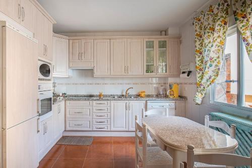a kitchen with white cabinets and a table at Casa Rural La Nava del Concejo in Navaconcejo