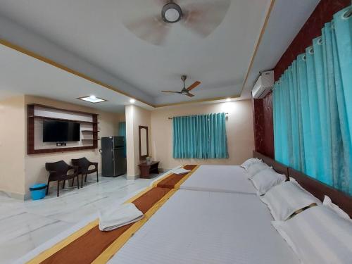 a large room with two beds and a flat screen tv at ICONIC Hotel Digha in Digha
