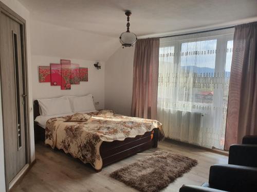 a bedroom with a bed and a large window at Casa Destinatia Perfecta Moieciu in Moieciu de Jos