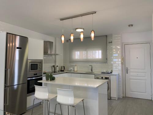 a white kitchen with a large island in the middle at Tulipanes Benalmádena - Parking privado in Benalmádena