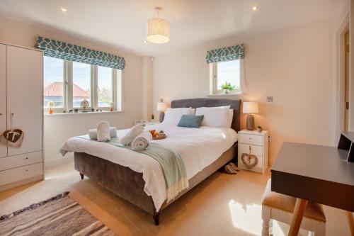 a bedroom with a bed with a desk and windows at Choseley Cottage - Norfolk Cottage Agency in Docking