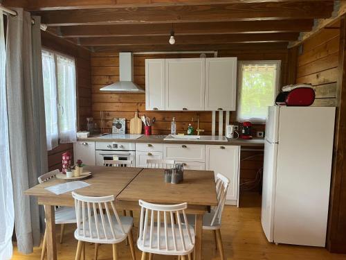 une cuisine avec une table en bois et un réfrigérateur blanc dans l'établissement Chalet du Trèfle, à Chalais