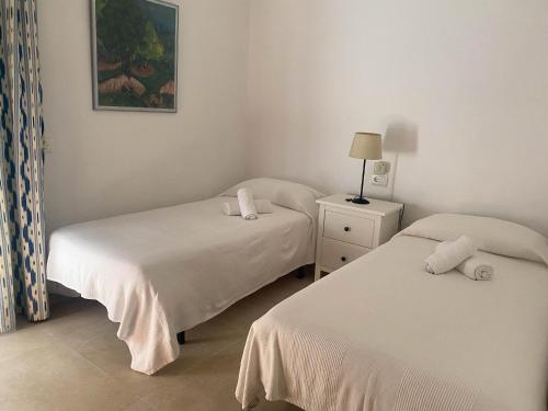 Un dormitorio con dos camas y una lámpara en una mesita de noche. en Can Botana 3, en Cala de Sant Vicent