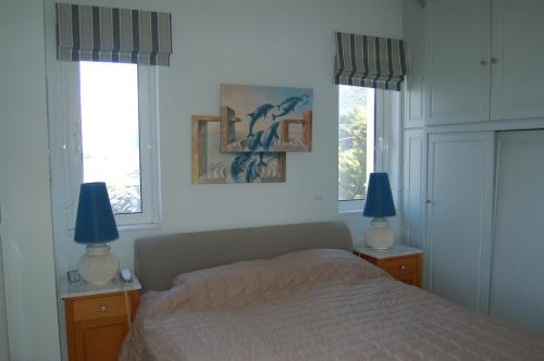 a bedroom with a bed with two lamps and two windows at Villa sul Mare in Chalkida