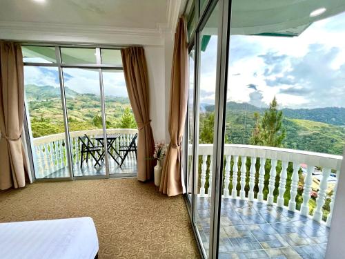 a room with a bed and a balcony with a view at JR RESORT in Ranau