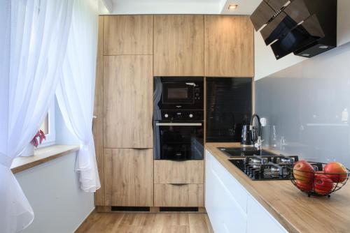 a kitchen with wooden cabinets and a stove top oven at Apart-Wita in Wadowice