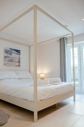 a white bedroom with a white canopy bed at Sennen Cove Cottage in Sennen Cove