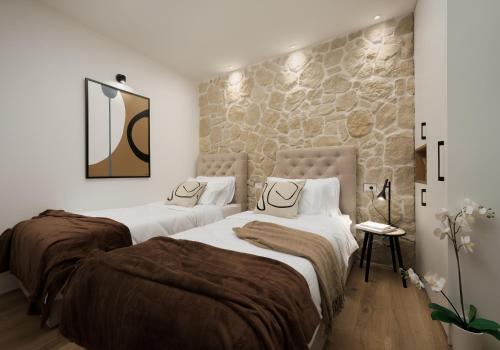 Apartment City Walls in Old Town of Rovinj في روفينج: سريرين في غرفة نوم بحائط حجري