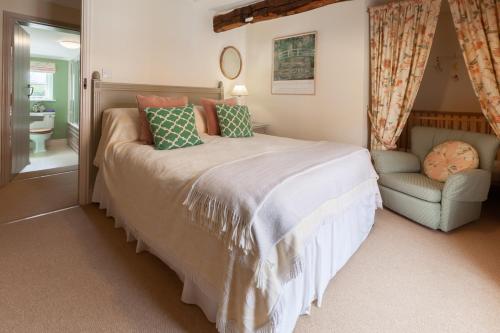 a bedroom with a large bed and a chair at Bluebell Cottage - Norfolk Cottage Agency in Burnham Market