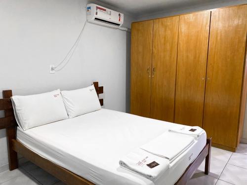 Un dormitorio con una cama con un armario de madera y publicidad. en River Class Hotel, en Petrolina