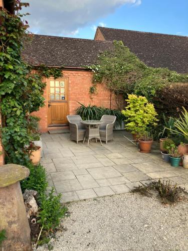 a patio with two chairs and a table in front of a building at The Burrow in Wellesbourne Hastings