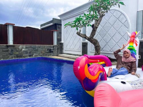 Ein kleines Mädchen sitzt auf einem aufblasbaren Floß im Pool in der Unterkunft Villa Twin with Private Pool by Masterpiece VIlla in Batu