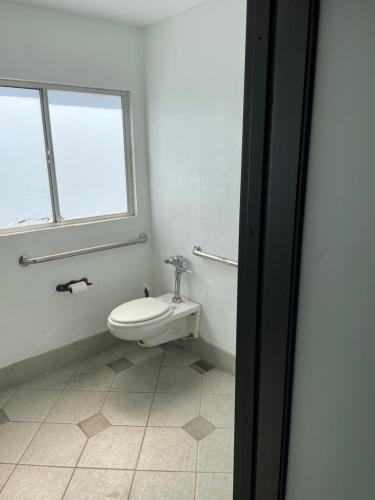 a white bathroom with a toilet and a window at Culver City Hostel in Los Angeles
