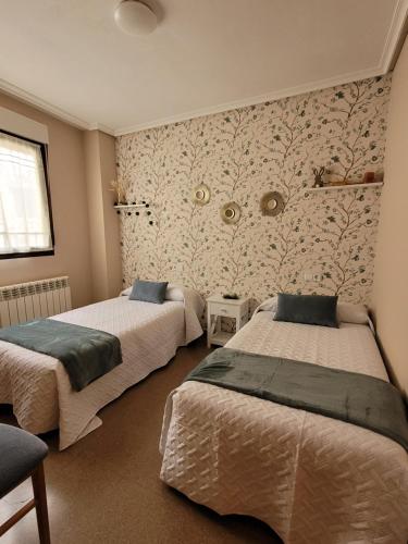 um quarto com 2 camas e uma parede estampada em Casa Petra y Armando em Anguiano