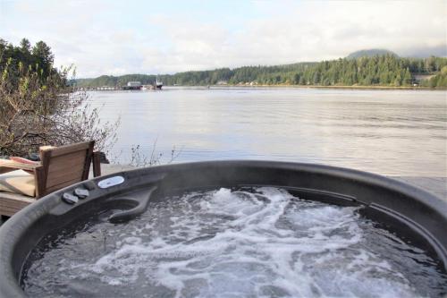 a bath tub filled with water next to a body of water at Private Oceanfront Room With Hot Tub & Firepit - Shore Thing in Ucluelet