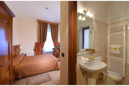 Hotel Acqui & Centro Benessere في أكوي تيرمي: حمام مع سرير ومغسلة وحمام مع مغسلة