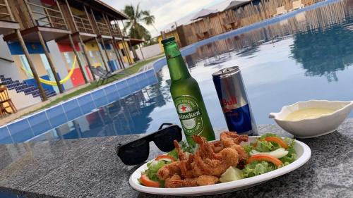 talerz jedzenia i butelkę piwa przy basenie w obiekcie Sol Beach w mieście São Miguel dos Milagres