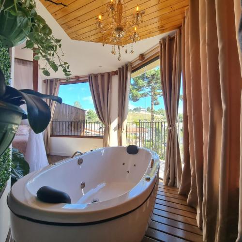 a bath tub in a room with a large window at Recanto dos Moinhos - Boutique Hotel in Campos do Jordão