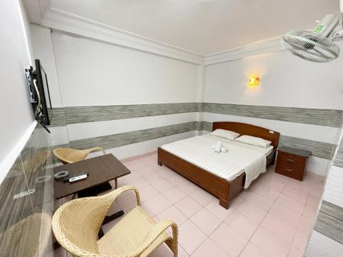 Schlafzimmer mit einem Bett, einem Tisch und Stühlen in der Unterkunft Huy Hoàng Hotel in Ho-Chi-Minh-Stadt