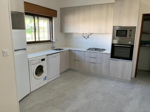 a kitchen with white cabinets and a washer and dryer at Casa da Serra in Quinta do Anjo